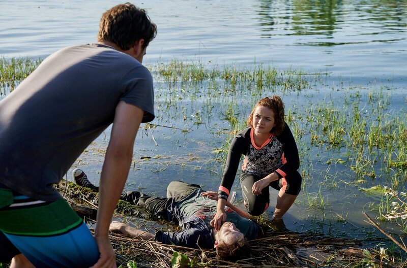 Das morgendliche Stand-up-Paddling von Jakob Frings (Max König, l.) und Julia Demmler (Wendy Güntensperger, r.) in der Liebesbucht findet ein jähes Ende, als Julia einen leblosen Körper am Ufer des Bodensees entdeckt. – Bild: ARD/​Nicolas Gradicsky