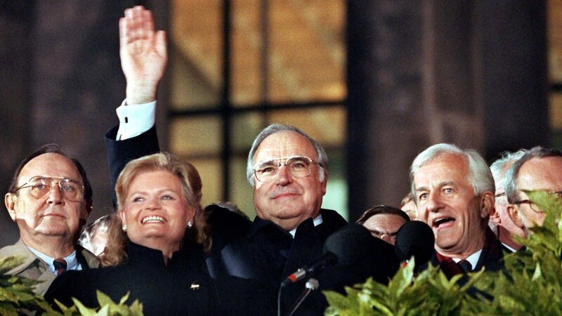 Wiedervereinigung: Bundeskanzler Helmut Kohl (M.) winkt zum Geläut der Freiheitsglocke von der Freitreppe des Berliner Reichstages. Links neben Kohl stehen Außenminister Hans-Dietrich Genscher und Hannelore Kohl, rechts von ihm Bundespräsident Richard von Weizsäcker. – Bild: ZDF