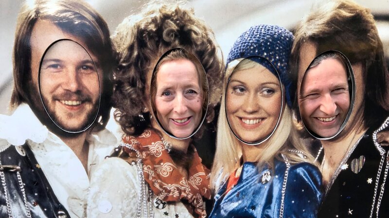 Entertainerin Kiona und Kreuzfahrtdirektor Jöhrn Hofer beim Besuch des ABBA-Museums, wo sie ihre Köpfe durch ein ABBA Plakat stecken. – Bild: BR/​Bewegte Zeiten Filmproduktion GmbH/​Julia Jancso