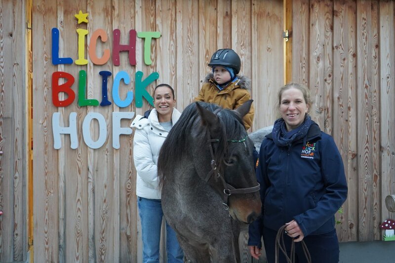 Der kleinen Felix sitz am Pferd, mit dabei sind Andrea Schlager (l.) und die Leiterin des Lichtblickhodes, Roswitha Zink. – Bild: ServusTV /​ Sonja Eichholzer /​ Degn Film