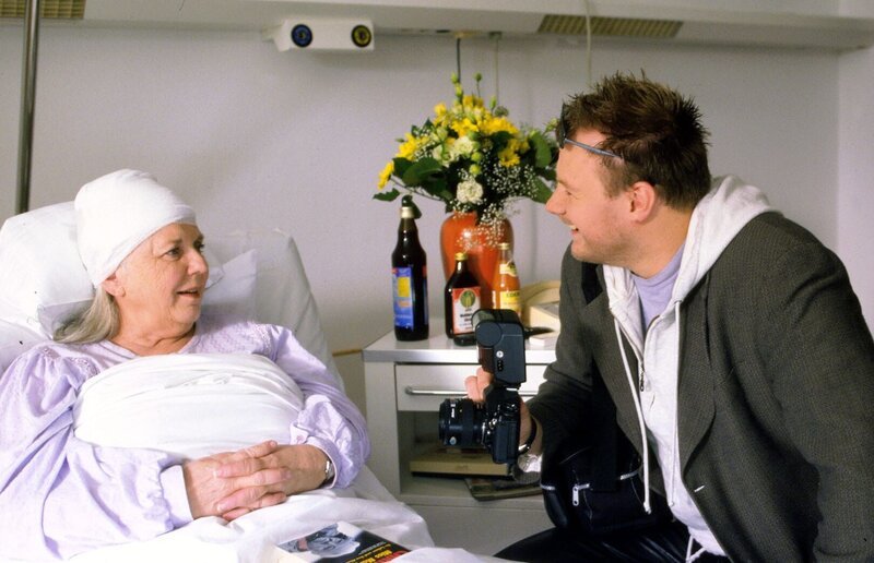 Im Krankenhaus wird Resi Berghammer (Ruth Drexel, l.) von Lokal-Reporter Goetz (Michael Grimm, r.) besucht, der sie geschickt ausfragt. Bereitwillig gibt sie Auskunft über das Ableben des Schlagersängers Tony Gordon … – Bild: SAT.1 /​ Magdalena Mate