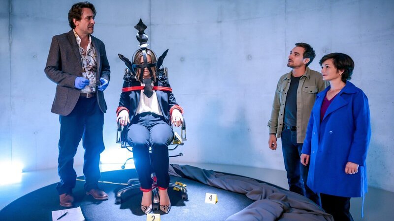 Die Eröffnung der Ausstellung „Schande“ des Museums „Spirit of Linz“ entpuppt sich als böse Überraschung. Als der Vorhang fällt, um das Herzstück der Ausstellung – die Schandmaske – zu präsentieren, erscheint dahinter die Leiche der Museumsdirektorin Stella Böhm. – Bild: ZDF und Stefanie Leo