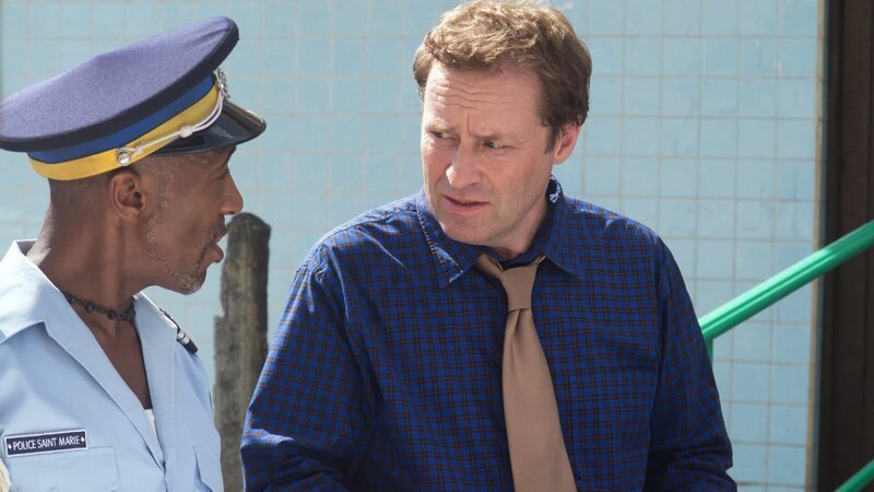 Der Engländer DI Jack Mooney (Ardal O’Hanlon, r.) wird schon nach kurzer Zeit auf der karibischen Insel um Hilfe bei den Ermittlungen zu einem Mordfall gebeten. Dwayne (Danny John-Jules, l.) informiert ihn über den aktuellen Stand der Ermittlungen. – Bild: ZDF und Thierry Cheutin
