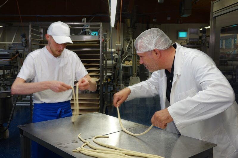 Von links: Franz Piller und Alexander Herrmann an der Brezenteigschlingmaschine in der Produktionsstätte der Bäckerei Piller in Karlsfeld. – Bild: Jürgen Endriß /​ BR