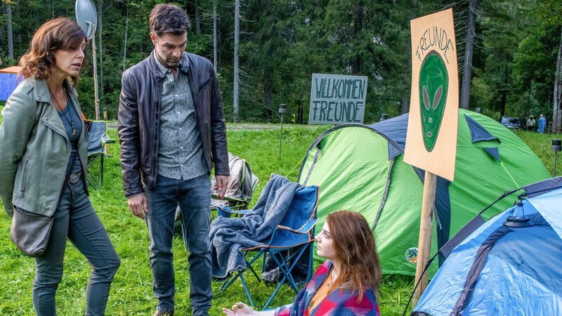 UFO-Alarm in den Bergen: Seit geraumer Zeit versammeln sich UFO-Spotter in Kitzbühel und erhoffen sich, dass Außerirdische endlich mit ihnen Kontakt aufnehmen. Am Morgen nach einer der Sichtungen wird eine Frau ermordet im Wald gefunden. Nina (Julia Cencig, l.) und Lukas (Jakob Seeböck, M.) ermitteln bei den UFO-Spottern und stoßen auf einen ehemaligen Professor für Astronomie. – Bild: Stefanie Leo