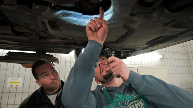 Ein Automechaniker inspiziert ein Auto. – Bild: Warner Bros. Discovery, Inc.