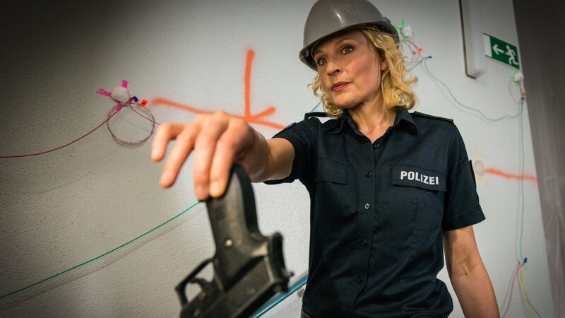 Melanie (Sanna Englund) wurde von Lutger Dörr als Geisel genommen. Wenn sie ihm ihre Waffe nicht gibt, drückt er sofort den Auslöser und sprengt alles in die Luft. – Bild: Boris Laewen