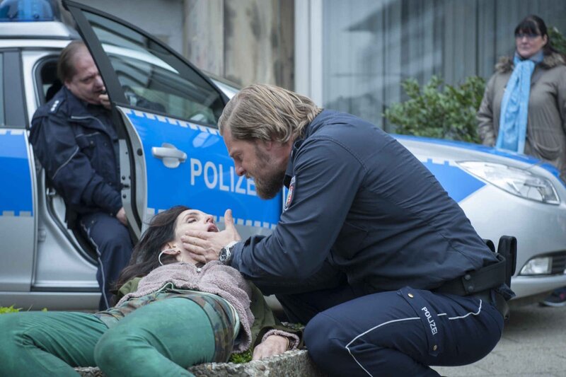 Im Gegensatz zu seinem Streifenkollegen Udo Bickenberg (Jürgen Tarrach, l.), der nur Dienst nach Vorschrift macht, bringt sich Mick (Henning Baum, r.) immer voll ein und hat keine Berührungsängste vor kollabierenden Drogensüchtigen (Nathalie Taly Journo) … – Bild: SAT.1 /​ Martin Rottenkolber