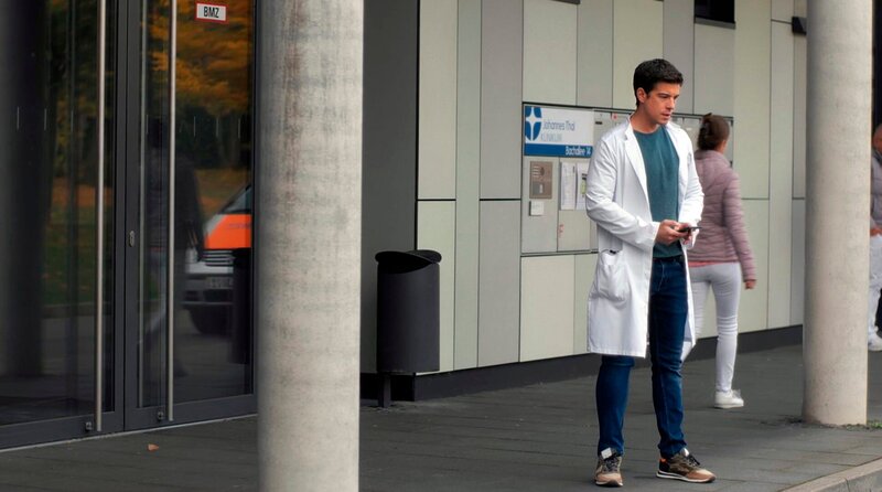 Dr. Ben Ahlbeck (Philipp Danne) beendet sein Telefonat vor dem JTK. – Bild: ARD/​Jens-Ulrich Koch