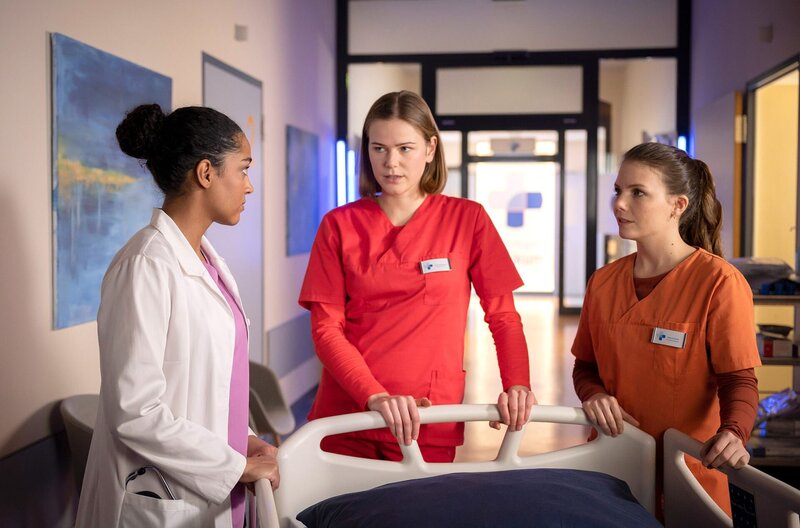 Dr. Emma Jahn (Elisa Agbaglah, l.) erklärt Louisa ((Llewellyn Reichman, M.) und Maxi (Leonie Rainer, r.) weshalb Frau Otruba nicht mehr zu helfen ist. – Bild: ARD/​Felix Abraham