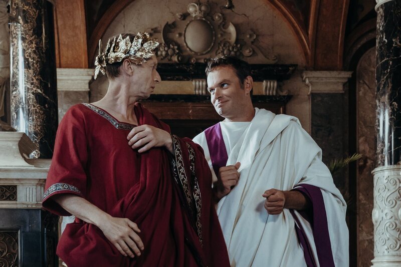 Decimus Brutus (Sebastian Herrmann) führt Cäsar (Thorsten Krohn) zu einer Senatssitzung. – Bild: KiKA/​Sabine Finger
