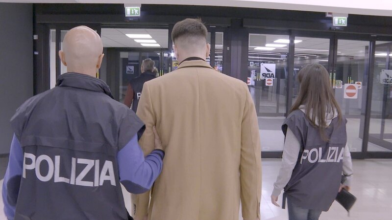 Der Polizist bringt den verhafteten Passagier zum Polizeiauto. – Bild: National Geographic