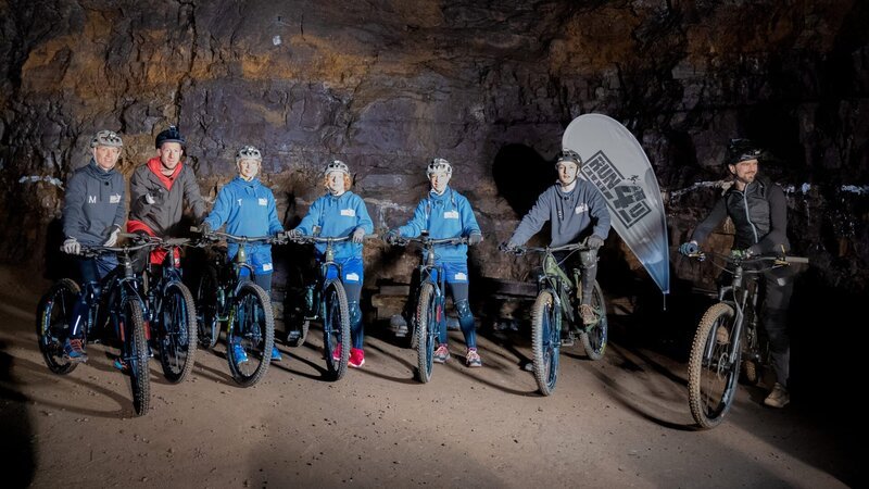 V.l.: Maddox, Lars, Tove, Zoe, Vanessa, Esra und Guide Lucas im Besucherbergwerk Kamsdorf. Auf sie wartet eine Bike-Tour durchs Bergwerk. – Bild: MDR/​Cine Impuls Leipzig