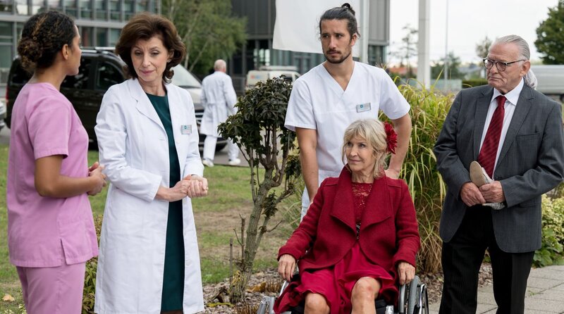 Marianne Plewig (Marita Breuer, 2.v.r. mit Komparsen) ist bereits zum zweiten Mal in kurzer Zeit im JTK. Dieses Mal möchte Sie Ihre Behandlung komplett abschließen, nachdem sie beim ersten Mal, vor den Augen von Emma Jahn (Elisa Agbaglah) und Karin Patzelt (Marijam Agischewa), das JTK wegen einer Einladung zum Tanztee verlassen hatte. – Bild: ARD/​Jens-Ulrich Koch