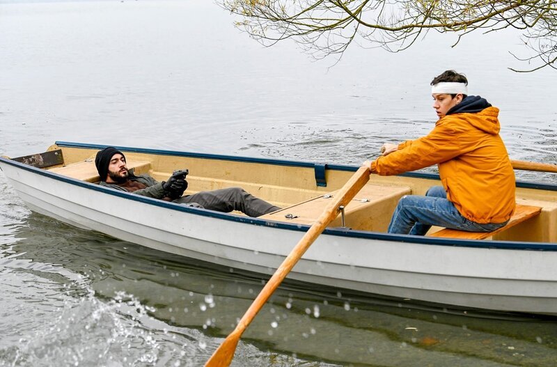 Der Entführer (Eidin Jalali, l.) zwingt Niklas Fehrenbach (Noah Calvin, r.) über den Bodensee zu rudern. – Bild: ORF/​Bavaria/​ARD/​SWR/​Laurent Trümper
