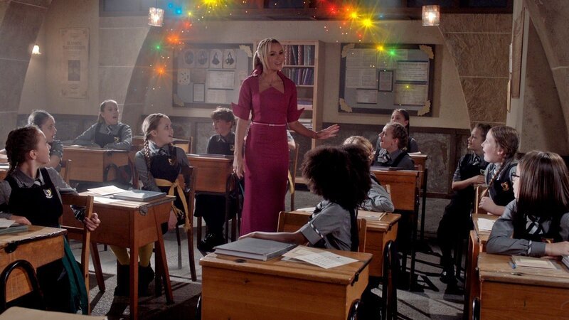 Die Lehrerin Frau Fünfzack (Amanda Holden) ist unerwartet auf der Graustein Akademie aufgetaucht. Der Zauberrat hat sie geschickt – sie soll in den Klassen moderne Zauberei unterrichten. Oder soll sie sogar die neue Direktorin werden? Die Erstklässler sind auf jeden Fall von ihrem modernen Zaubergesang begeistert. – Bild: BBC/​ZDF Enterprises