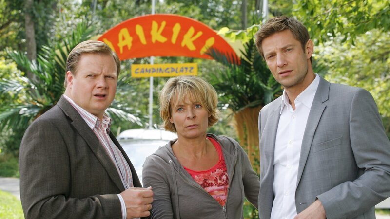 Die Rosenheimer Kommissare Hansen (Igor Jeftic, r.) und Hartl (Michael A. Grimm, l.) verdächtigen Dauercamperin Cornelia Meierling (Susanne Czepl, M.), die eine Affäre mit dem Opfer hatte. – Bild: Christian A. Rieger