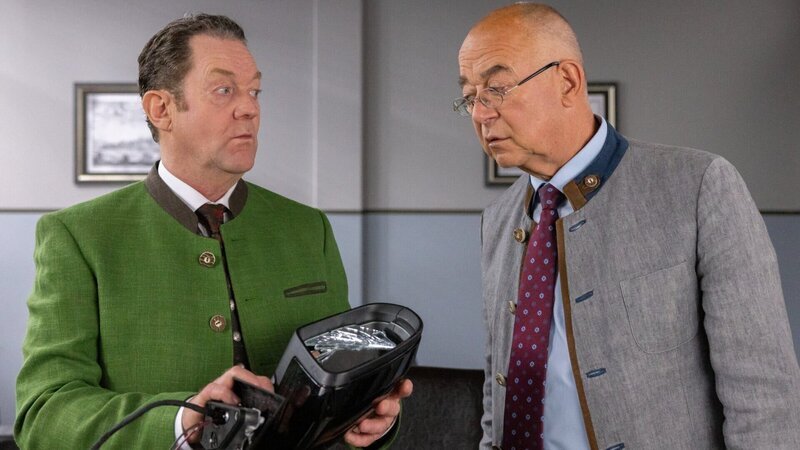Karl Schretzmayer (Jürgen Tonkel, l.), Bürgermeister von Ganting, hofft, dass Polizeidirektor Achtziger (Alexander Duda, r.) Ermittlungen im Fall seines kaputten Autospiegels einleiten wird. – Bild: ZDF /​ Linda Gschwentner
