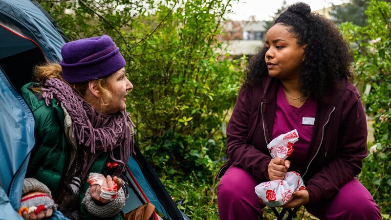 Zoe (Catherine Chikosi, r.) sitzt am Zelt von Brigitte Pawelski (Inga Dietrich l.), die im Park übernachtet hat und an der Hand verletzt ist. – Bild: Julia Feldhagen