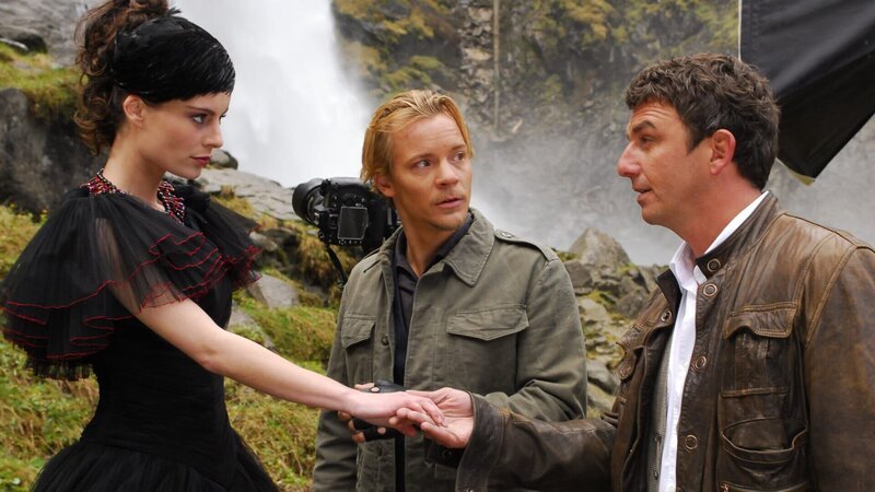 Der Fotograf Oliver (Christoph von Friedl, M.) hat Martin (Hans Sigl, r.) gerufen, damit er das kränkelnde Model Katja Stadler (Karolin Peiter, l.) für das Fotoshooting fit macht. – Bild: ZDF und Hans Seidenabel