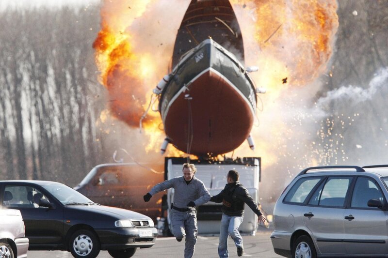 Bei der Explosion fliegt ein Boot durch die Luft: Semir (Erdogan Atalay, r.) und Gabor Fischer (Wilfried Hochholdinger) laufen um ihr Leben. – Bild: RTL /​ Guido Engels
