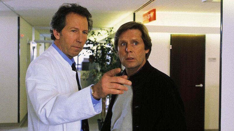 Chefarzt Dr. Ulrich Waldner (Hartmut Becker, li.) zeigt seinem Freund und Kollegen Dr. Stefan Frank (Sigmar Solbach), in welchem Zimmer dessen Vater nach einem Kreislaufkollaps liegt. – Bild: MG RTL