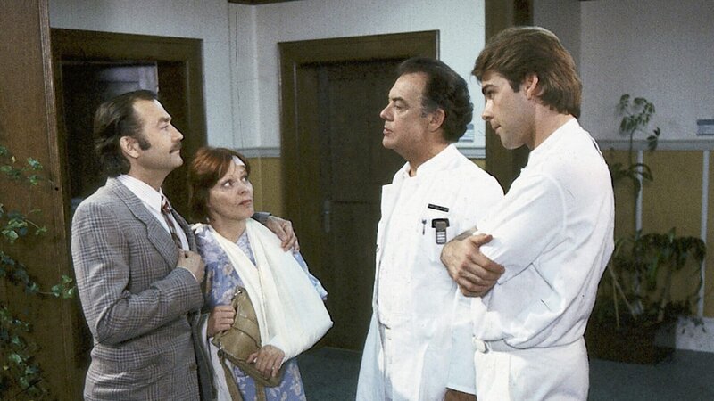 Konrad Pesch (Jürgen Schmidt) bringt Gertrud Melldorf (Loni von Friedl) ins Krankenhaus zurück und versucht gegenüber Klaus (Klausjürgen Wussow) und Udo Brinkmann (Sascha Hehn) die Verletzung als ein Unfall hinzustellen. – Bild: Thomas Waldhelm