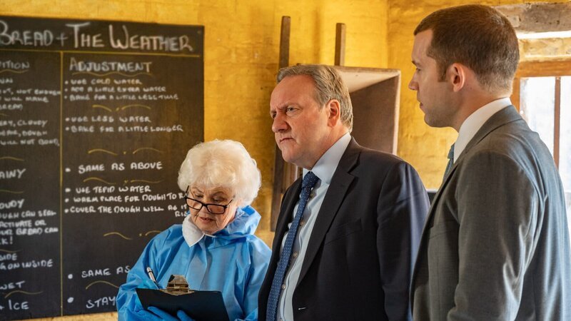 Mehrere Dorfbewohner erlitten eine Mutterkornvergiftung. Rechtsmedizinerin Fleur Perkins (Annette Badland) kann die Ursache auf eine Ladung Körner zurückverfolgen, die in Brötchen verarbeitet wurden. Inspector John Barnaby (Neil Dudgeon, M.) und sein Assistent DS Jamie Winter (Nick Hendrix) fragen sich nun, ob hinter der Sache ein Versehen oder Absicht steckt. – Bild: Mark Bourdillon/​All3Media