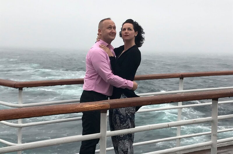 Die Reiseleiter Maika und Bernd stehen an Bord der „Grand Lady“ Modell für das Fotobuch des Bordfotografen und versuchen eine gute Figur zu machen. – Bild: BR/​Bewegte Zeiten Filmproduktion GmbH/​Julia Jancso