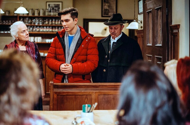 Felix tritt den Gang nach Canossa an und entschuldigt sich bei den Gästen. Von links: Theresa Brunner (Ursula Erber), Felix Brunner (Shayan Hartmann) und Lorenz Schattenhofer (Werner Rom). – Bild: BR/​Nadya Jakobs