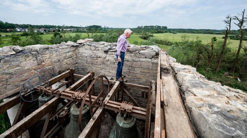 Küster Paul Dirwinkel steht auf dem Glockenturm des über 1000 Jahre alten Turms der Hellinghauser St.Clemens-Kirche, der ältesten Steinkirche Westfalens. Das Dach hat der Tornado zu Boden geworfen. – Bild: WDR/​dpa