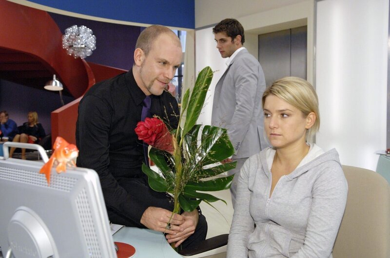 Gerrit kommt bester Laune zu Anna an den Schreibtisch. Er weiß bereits über die desaströsen Verkaufszahlen von „Crash“ Bescheid. v.l.n.r.: Gerrit (Lars Löllmann), Jonas (Roy Peter Link), Anna (Jeanette Biedermann) – Bild: SAT.1 /​ Claudius Pflug Eigenproduktionsbild frei