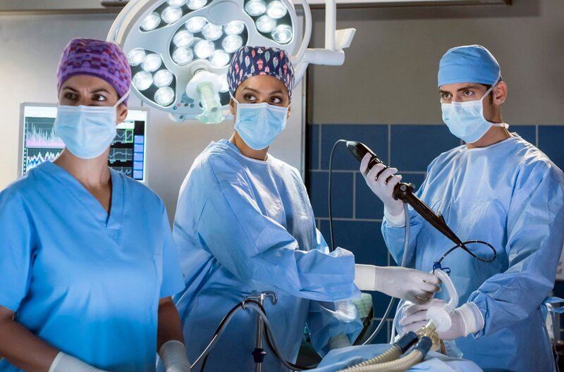Dr. Leyla Sherbaz (Sanam Afrashteh, l.), Vivienne Kling (Jane Chirwa, M.) und Dr. Niklas Ahrend (Roy Peter Link, r.) untersuchen die Musikerin Kim Burisch mittels einer Bronchoskopie. – Bild: ARD/​Jens Ulrich Koch