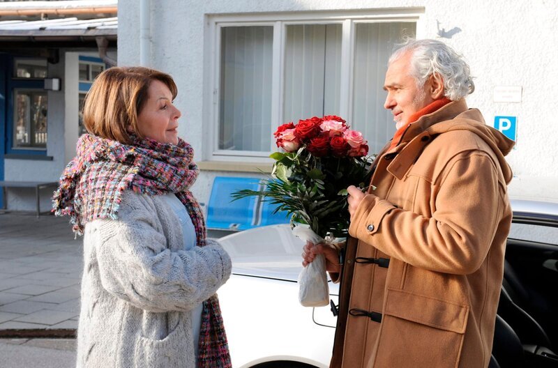 Rosi ist überrumpelt, als Karl sie bei ihrem unverbindlichen Treffen scheinbar mit roten Rosen überrascht. Von links: Rosi Kirchleitner und Karl. – Bild: BR/​Marco Orlando Pichler
