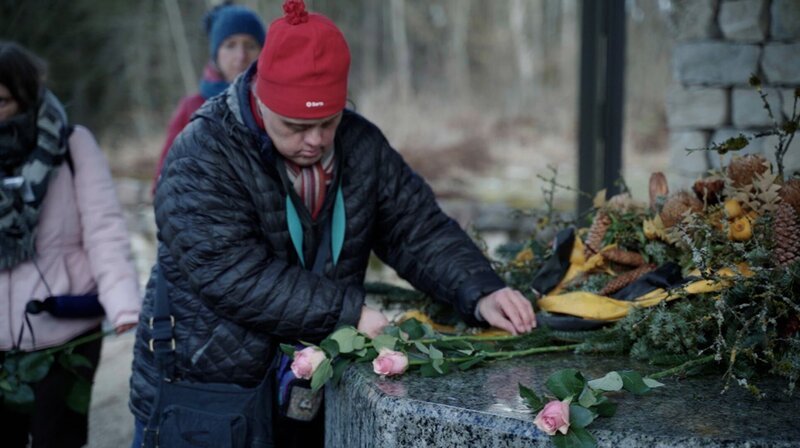 Mitglieder des inklusiven Ensembles des Theaters Reutlingen „Die Tonne“ legen Blumen an der Gedenkstätte Grafeneck nieder. – Bild: WDR/​KHM Köln