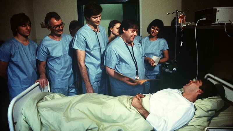 Dr. Udo Brinkmann (Sascha Hehn) hat alles gut überstanden. Der Arzt (Andreas Mannkopff) und sein Team sind sehr glücklich darüber. – Bild: ZDF und Thomas Waldhelm