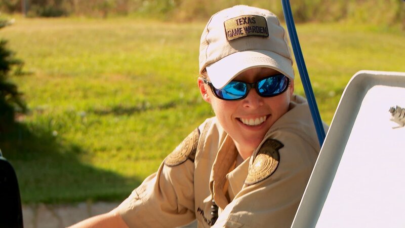 Warden Jennifer Provaznik smiling while leaning on car. – Bild: Animal Planet /​ Discovery Communications, LLC