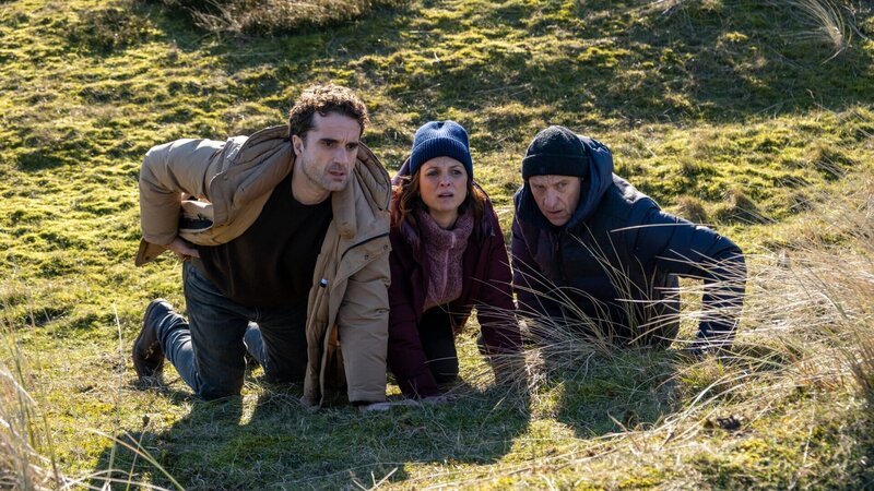 Aufregung auf Sylt: Schüsse fallen und Carl Sievers (Peter Heinrich Brix, r.) scheint im Visier zu sein. Hinnerk Feldmann (Oliver Wnuk) und Ina Behrendsen (Julia Brendler) suchen mit ihrem Chef Schutz hinter einem Hügel. Wer hat es auf den Hauptkommissar abgesehen? – Bild: ZDF und Manju Sawhney