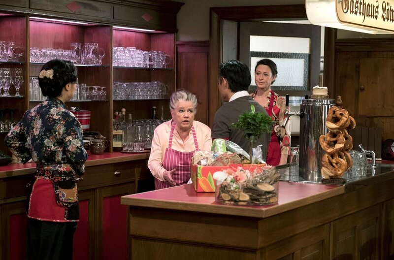 Leni ist mit der Kocherei für ihren „Herz zu Haus Service“ völlig überfordert und vergreift sich Tu gegenüber ordentlich im Ton. v.li.: Oanh (Yi Chi), Leni (Heidi Vogel-Reinsch), Tu (Maverick Quek), Stefanie Rabenalt (Nadine Ketterer) – Bild: SWR/​Schweigert