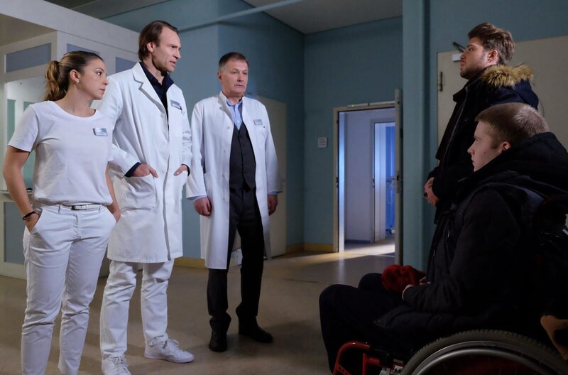 Als Kris Haas (Jascha Rust, re.oben) und Dominik Lorenz (Jonah Rausch, re.unten) von ihrem illegalen Ausflug zurückkommen, werden sie erwartungsgemäß nicht gerade herzlich empfangen. Dr. Martin Stein (Bernhard Bettermann, 2.v.li.) wirft Kris Verantwortungslosigkeit vor, Oberschwester Arzu (Arzu Bazman, li.) möchte gern ihren geklauten Autoschlüssel zurück. Verblüffender Weise ist ausgerechnet Klinikleiter, Dr. Roland Heilmann (Thomas Rühmann, 2.v.li.), derjenige, der etwas Verständnis für die beiden Burschen aufbringt. – Bild: MDR/​Saxonia Media/​Sebastian Kiss