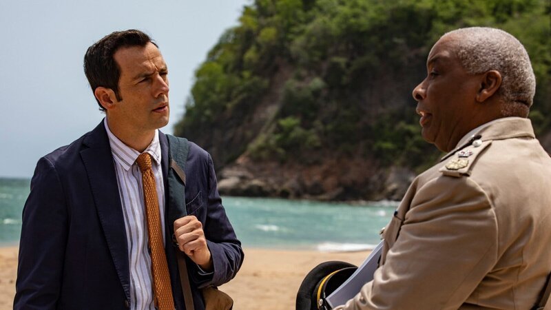 Detective Neville Parker (Ralf Little, l.) erfährt vom Polizeichef Selwyn Patterson (Don Warrington, r.) interessante Details über den Strand, die möglicherweise im Zusammenhang mit dem Mordfall stehen. – Bild: Honorarfrei