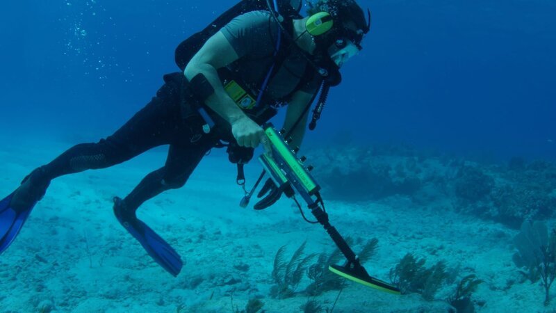 Darrell is underwater in scuba gear with a metal detector. – Bild: Discovery Communications