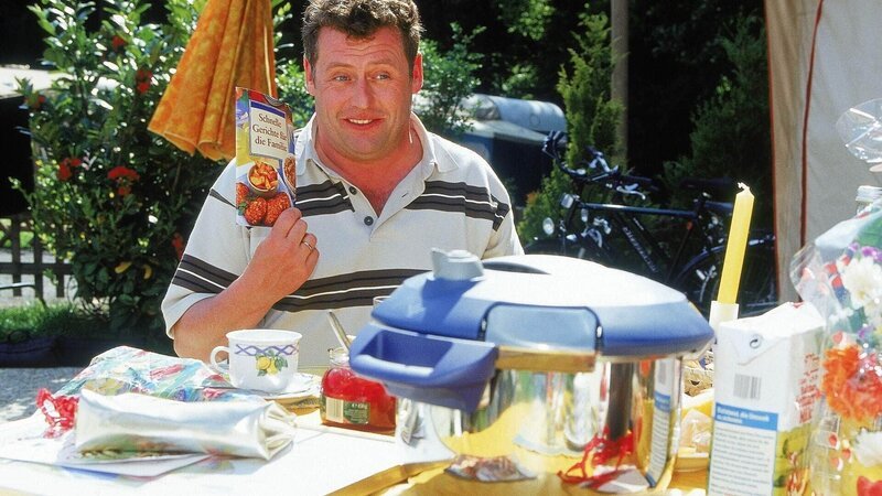 Stolz präsentiert Benno (Willi Thomczyk) sein Geburtstagsgeschenk für Uschi – einen Dampfkochtopf! Seiner Ansicht nach ein praktisches Geschenk, was die Arbeit erleichtert. Und ein Rezeptbuch ist auch noch dabei … – Bild: MG RTL D