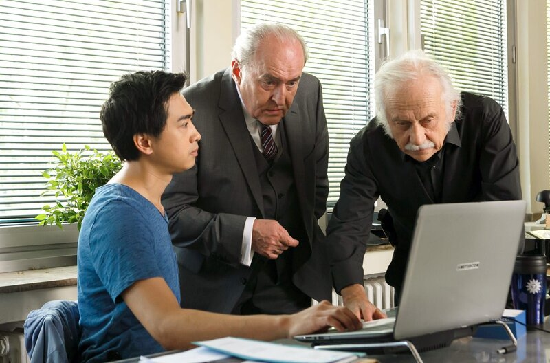 Hui Ko (Aaron Le, l.) präsentiert Plocher (Michael Prelle, M.) und Edwin Bremer (Tilo Prückner, r.) seine Theorie im Mordfall Teddy. – Bild: NDR/​ARD/​Kai Schulz