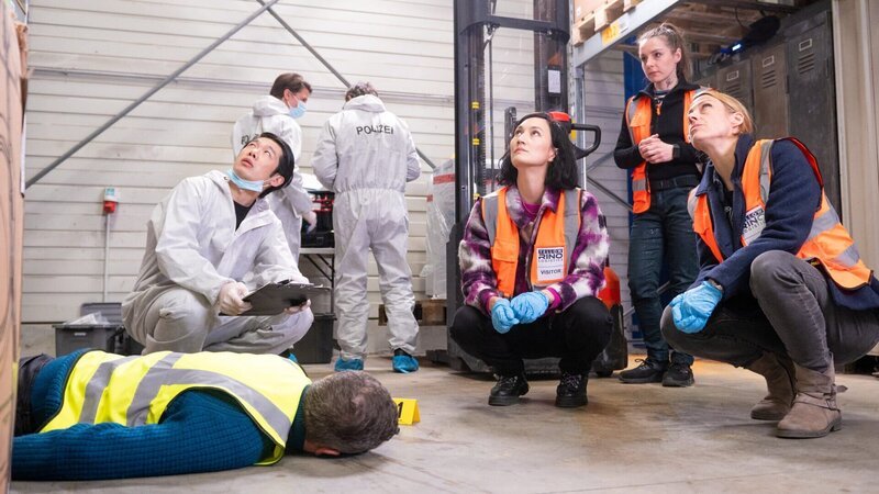 Pauline Hobrecht (Agnes Decker, 3.v.r.) und Tamara Meurer (Anja Pahl, r.) sind am Tatort in einer Lagerhalle. Thomas Brandner (Yung Ngo, l.) ist dabei die Spuren zu sichern. Die für die Sicherheit zuständige Mitarbeiterin Gina Gewitz (Marie Rosa Tietjen, 2.v.r.) kannte den Toten. – Bild: Britta Krehl