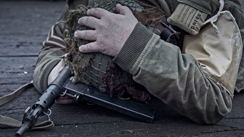 Der Soldat liegt in einer schützenden Position auf dem Boden. – Bild: FF1 Productions Inc /​ THE HISTORY CHANNEL