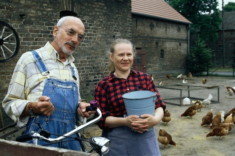 Natürlich gibt es auf einem Bauernhof Spatzen. Die Bäuerin (Hildegard Schröter, r.) zeigt Peter (Peter Lustig, l.), dass die Spatzen gerne den Hühnern die Körner wegfressen. – Bild: ZDF und Christiane Pausch.