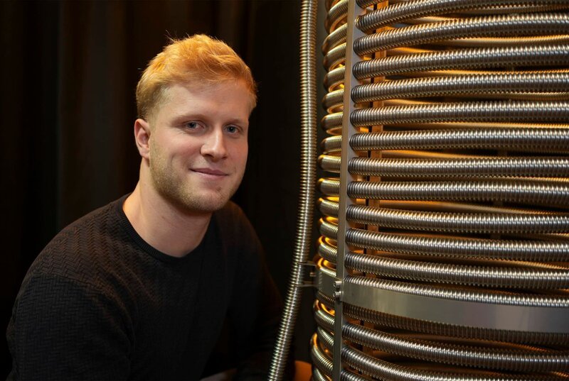 Erfinder Felix Drechsel (26) aus Weimar schaut auf seine Erfindung: ein Wärmetauscher für Mehrfamilienhäuser, der Energie aus Abwasser gewinnt. – Bild: MDR/​Sascha Kiesewetter