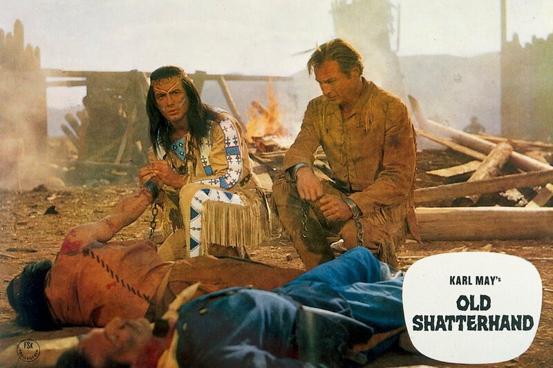 5. Winnetou (Pierre Brice) und Old Shatterhand (Lex Barker) knien vor dem toten Tujunga (Alain Tissier), der sich mit dem Pulvermagazin von Fort Grand selbst in die Luft gesprengt hat, um seinem Stamm den Sieg zu sichern. – Bild: CCC Filmkunst