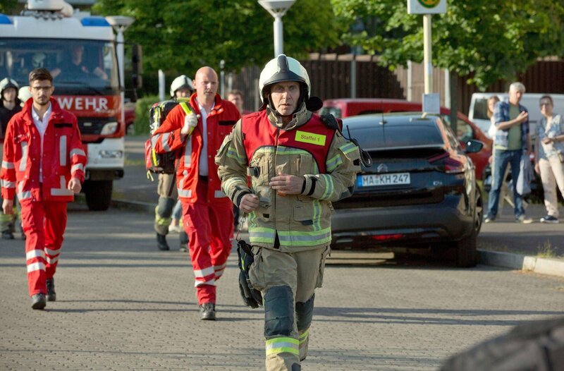 Ein Fahrer steckt mit seinem Kombi fest. Nina (Sabrina Amali) untersucht ihn und bricht auf dem Weg zum RTW zusammen. Das Team eilt zur Hilfe: Markus (Max Hemmersdorfer), Pio (Mark Zak, vorne) und Billy (Anna Schimigk) – Bild: ARD/​Volker Roloff